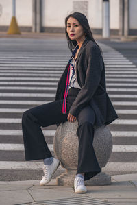 Portrait of young woman walking on footpath