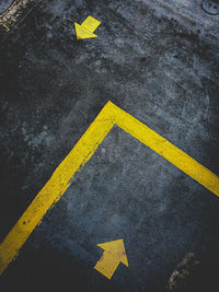 High angle view of yellow arrow sign on road