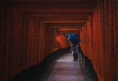 Rear view of man walking on footpath amidst building