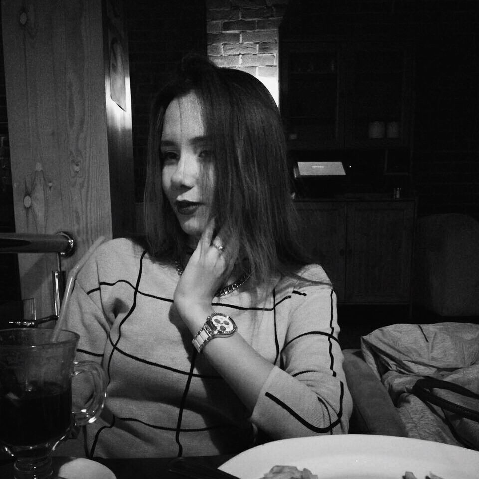 PORTRAIT OF YOUNG WOMAN SITTING BY TABLE