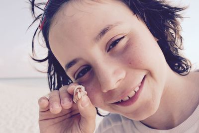 Close-up portrait of smiling girl holding hermit crab