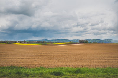 Scenic view of field against cloudy sky