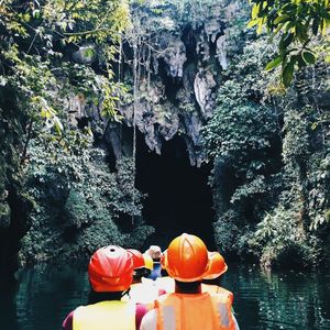 Rear view of people on boat in river entering cave