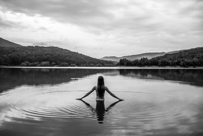 Rear view of woman in lake against sky