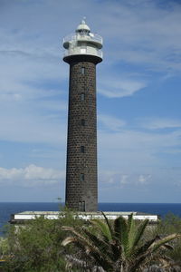 Lighthouse by sea against sky