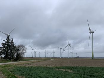 Windmills on field against sky