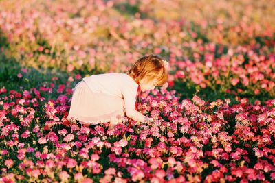 Side view of girl playing on flowerbed