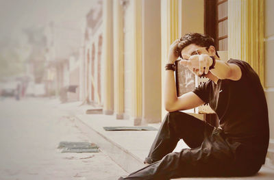 Woman holding camera while sitting outdoors