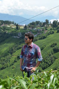 Young man standing on field against sky