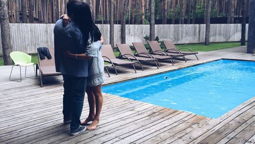 Couple embracing while standing at pool side