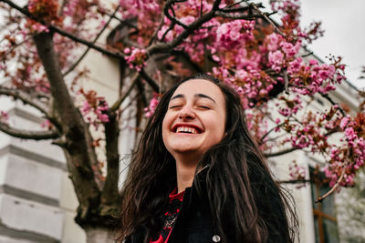 Portrait of young woman standing against trees