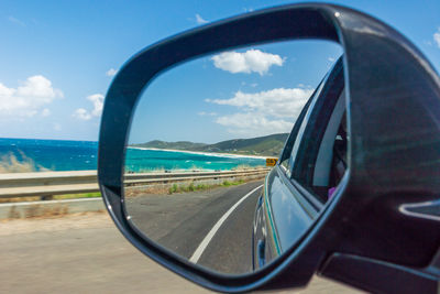 Reflection of great ocean road on side-view mirror of car