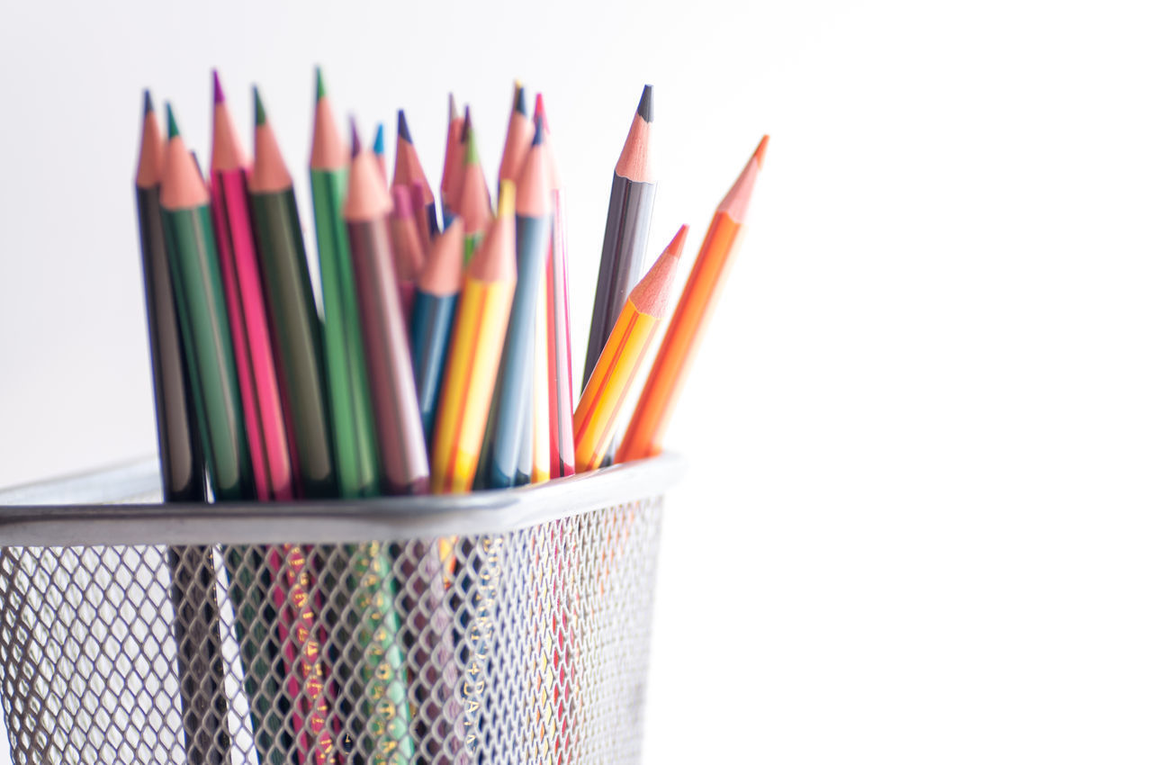 CLOSE-UP OF COLORED PENCILS AGAINST WHITE BACKGROUND