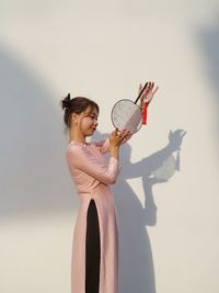 Portrait of young woman standing against wall