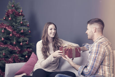 Young couple holding christmas tree at home