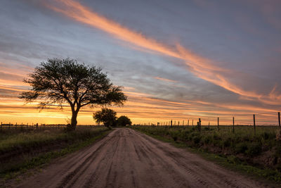 Dirt road against dramatic sky during sunset