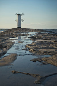 Lighthouse by sea against sky