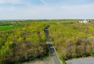 Road amidst trees on field against sky