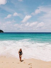 Woman standing on beach against sky