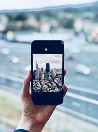 Close-up of hand holding mobile phone in city