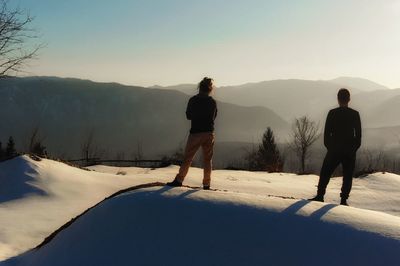 Rear view of man standing on snow against sky