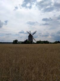 Traditional windmill on field against sky