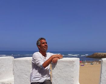 Full length of man on beach against clear blue sky