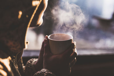 Close-up of woman holding coffee cup in the early morning winter atmosphere