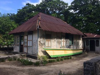 Abandoned house by trees against sky