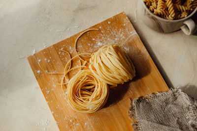 Homemade pappardelle raw pasta on wooden board in bright kitchen. raw tortiglioni pasta 