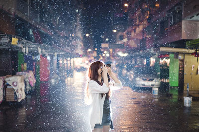 Woman standing on wet street in city