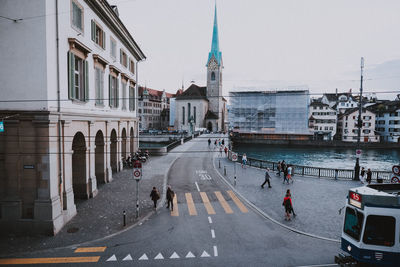 People walking on road by buildings in city