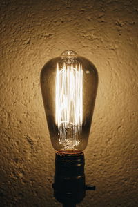 Illuminated light bulb against wall