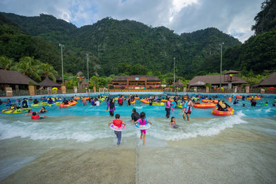 People in swimming pool against mountains