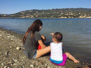 Siblings sitting by lake in city