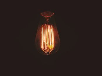 Close-up of illuminated light bulb against black background