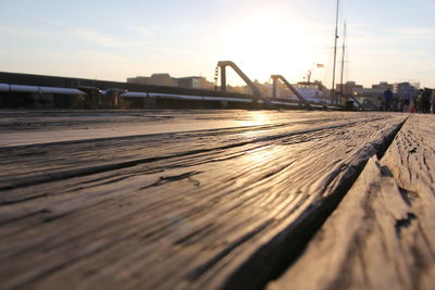 Surface level shot of wooden pier against sky during sunset