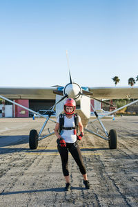 Young female skydiver in an airfield with plane in the back