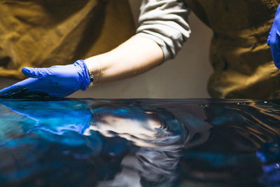 Detail of female resin artist working with her hands on large artwork