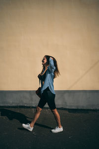 Full length of woman standing against wall