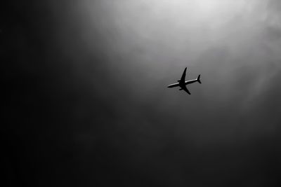 Low angle view of silhouette airplane flying against sky