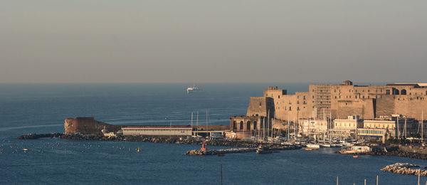 Scenic view of sea by buildings against clear sky