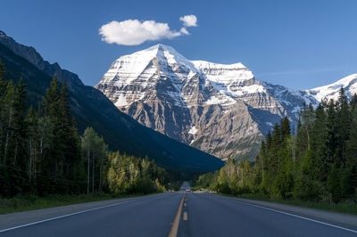 Road by snowcapped mountains against sky during winter