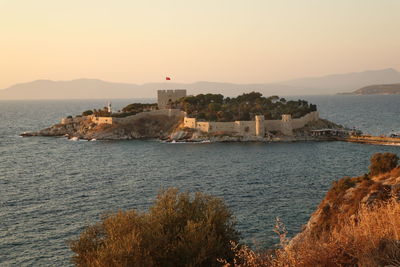 Scenic view of sea and buildings against sky during sunset