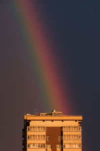 Low angle view of rainbow over buildings against sky