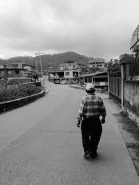 Rear view of man walking on road in city