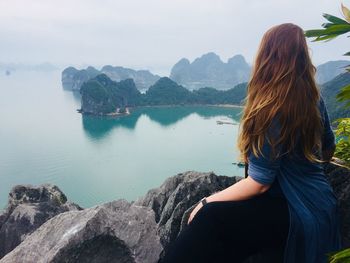 Woman looking at sea while sitting on mountain