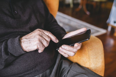 Hands of senior man using smartphone, close-up