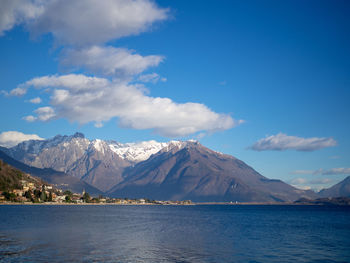 Scenic view of sea and snowcapped mountains against blue sky