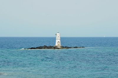 Lighthouse amidst sea against sky